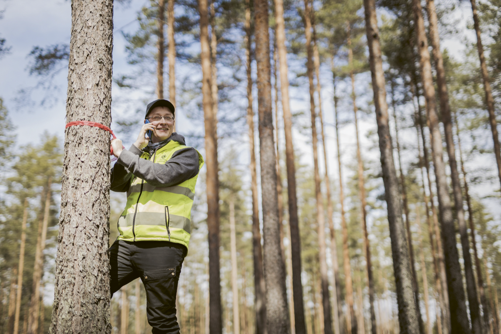 Metsäasiantuntija puhumassa puhelimeen metsässä.